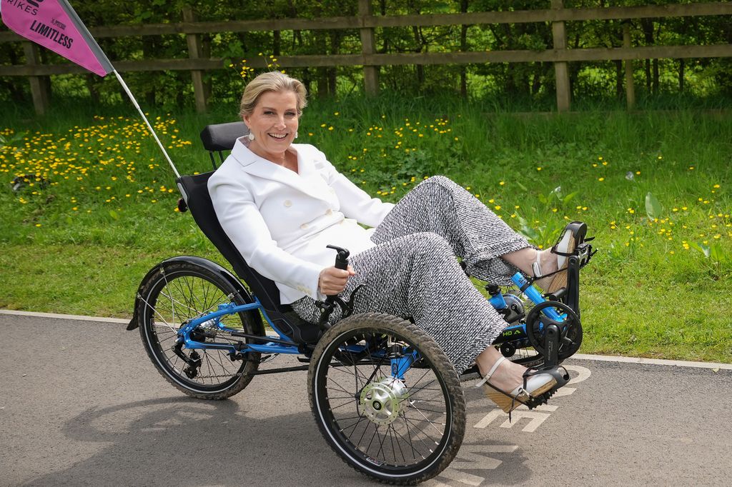 Sophie, Duquesa de Edimburgo andando de triciclo adaptativo com blazer branco