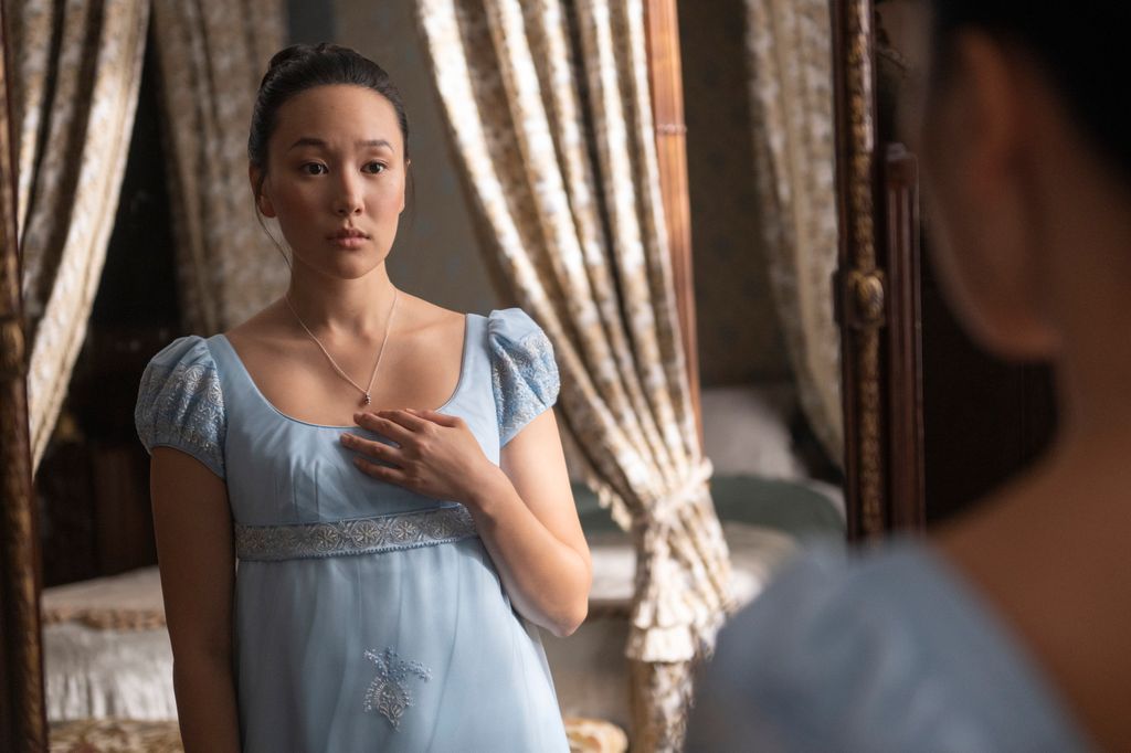 woman in 19th-century clothing looking in mirror