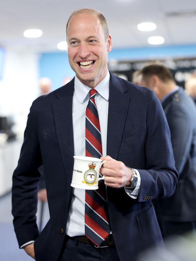 Princw William smiling and holding a mug