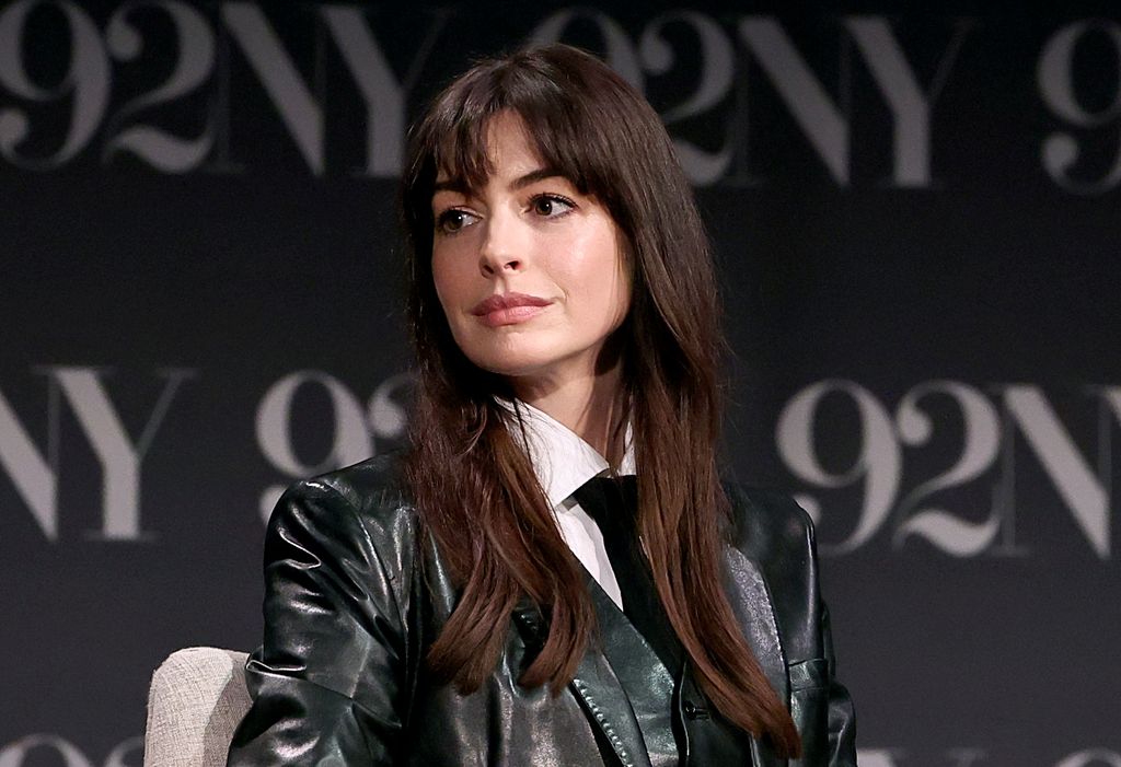 Anne Hathaway in a black leather jacket looking off to the side