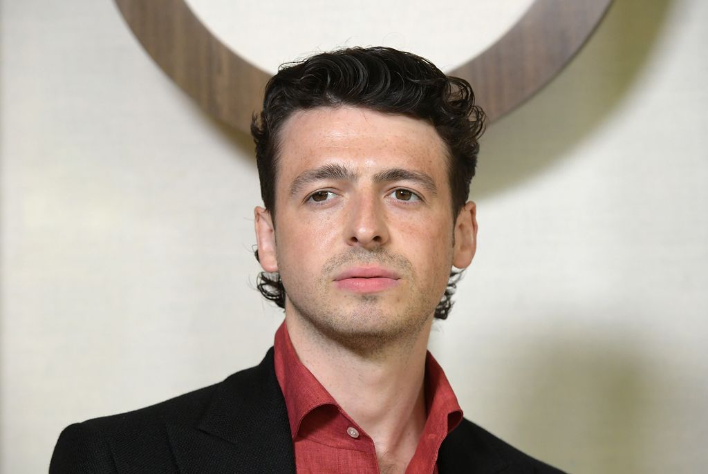 Anthony Boyle shoulders up in red shirt and black blazer