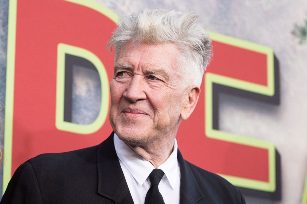 David Lynch in a black suit in front of red lettering