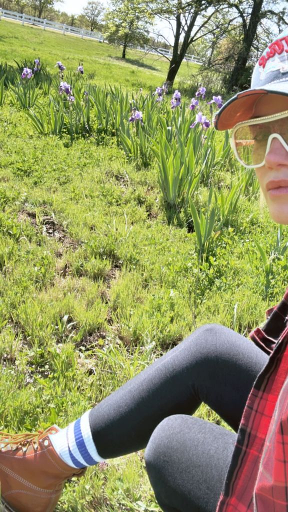 woman in casual clothes sitting in garden with iris flowers