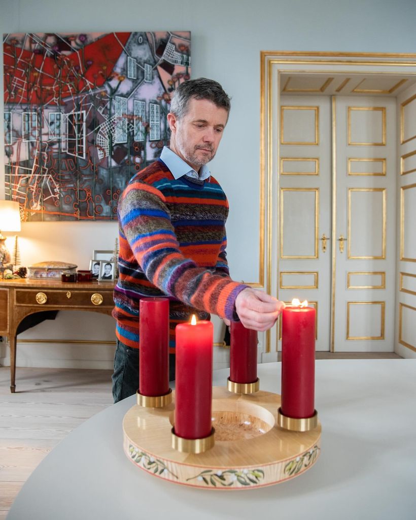Crown Prince Frederik wearing striped jumper and lighting a candle
