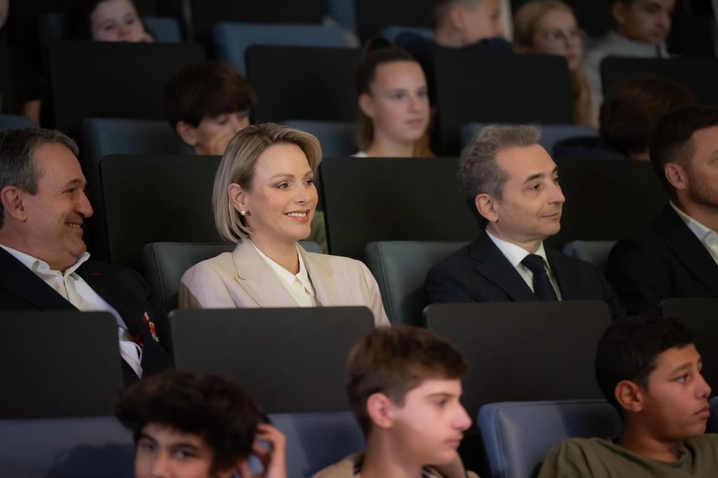 Princesa Charlene sorrindo nos assentos do auditório