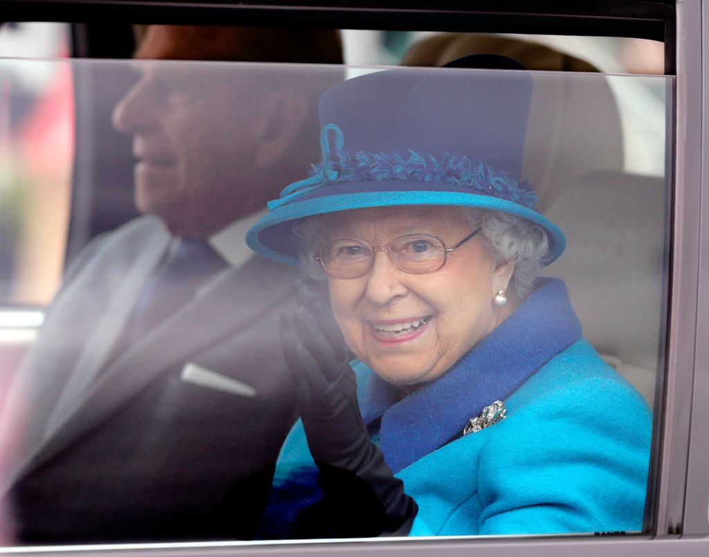queen in car wearing blue hat 