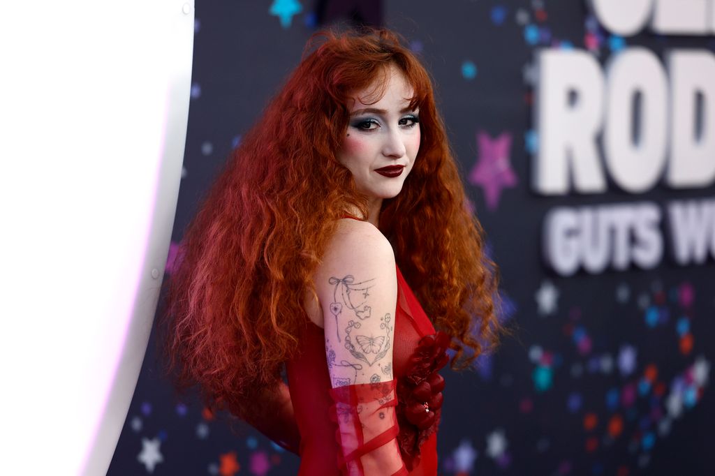 Chappell Roan in red dress and gloves while on red carpet for the premiere of Netflix's Olivia Rodrigo: GUTS World Tour 