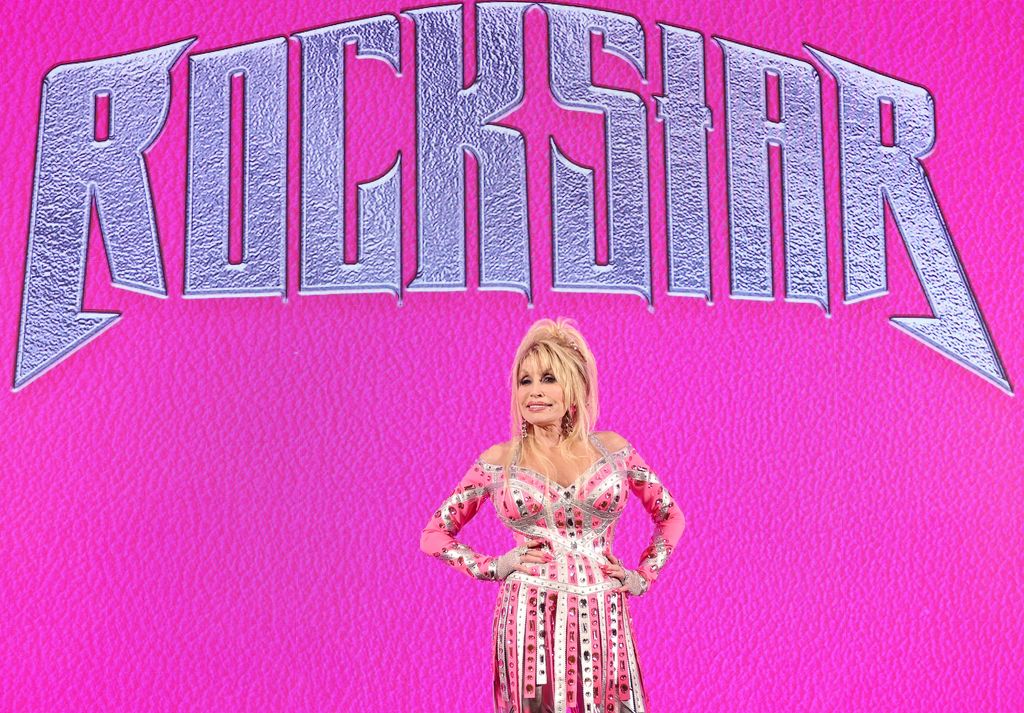 dolly parton standing in front of pink rockstar sign