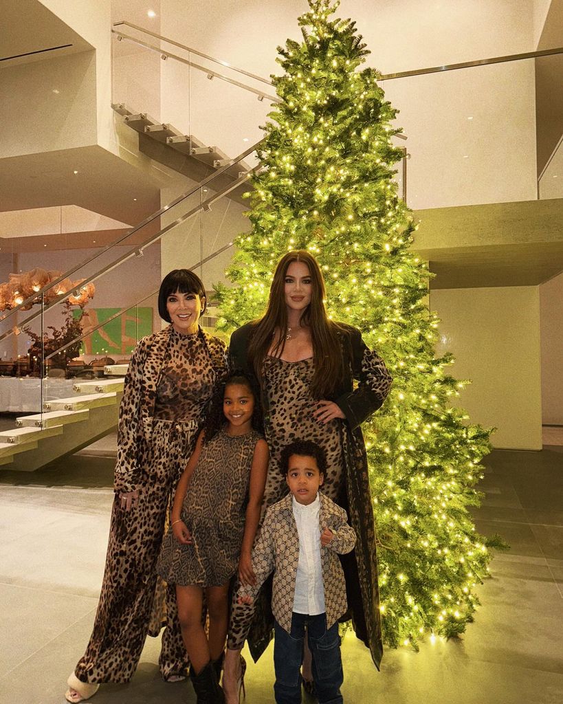 kris jenner with khloe kardashian and her kids posing in front of christmas tree