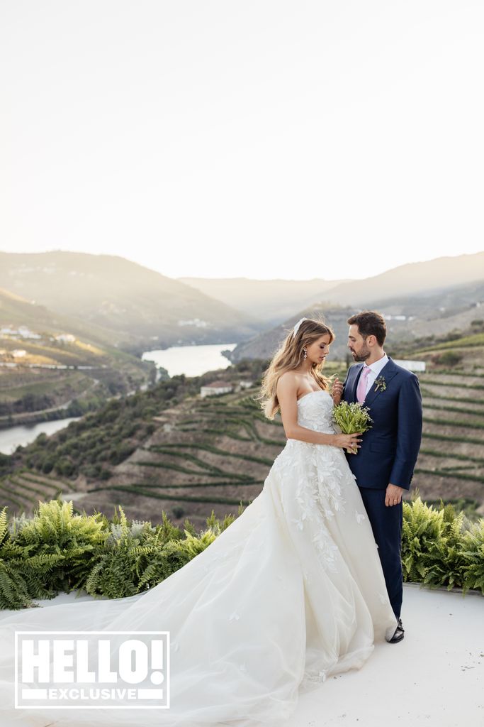 The bride looks down at her groom as they pose against a beautiful setting in the Portugese countryside