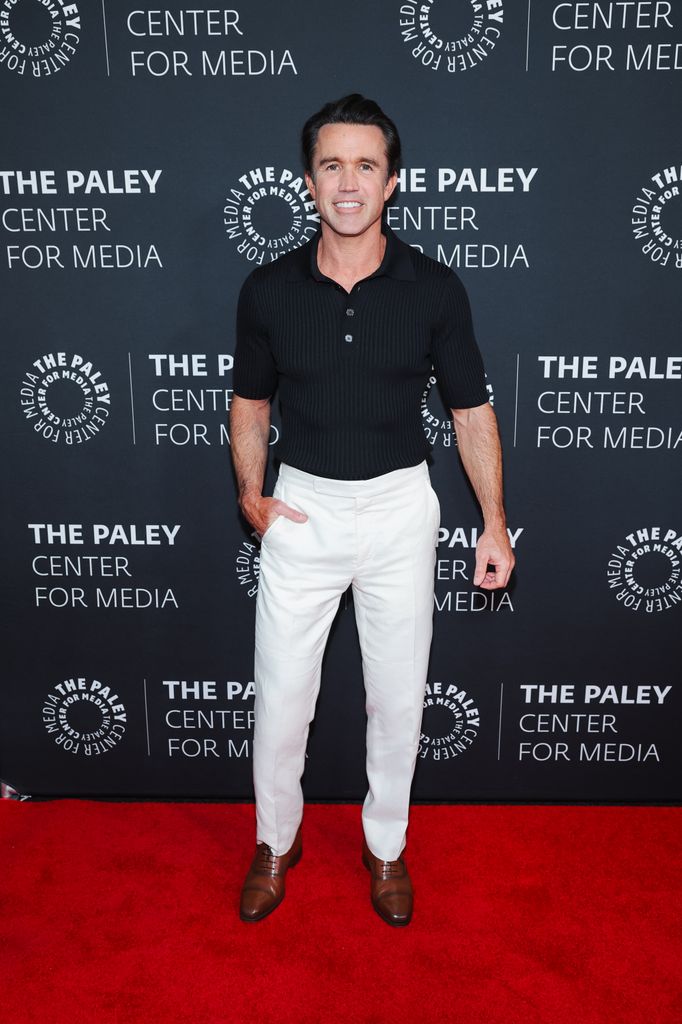 rob mcelhenney on red carpet wearing white pants and black top