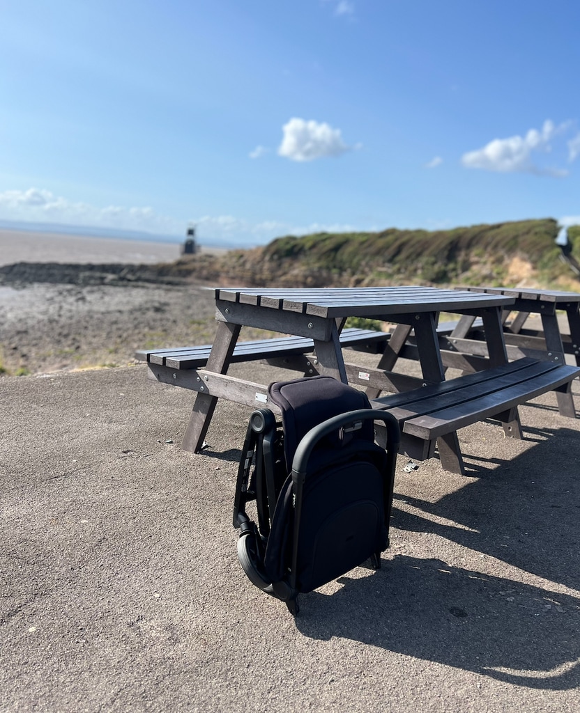 Pram folded up by bench at the seaside 