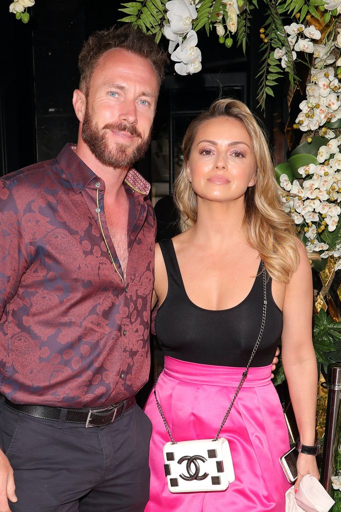James Jordan in a red shirt and Ola Jordan in black and pink against the backdrop of white flowers