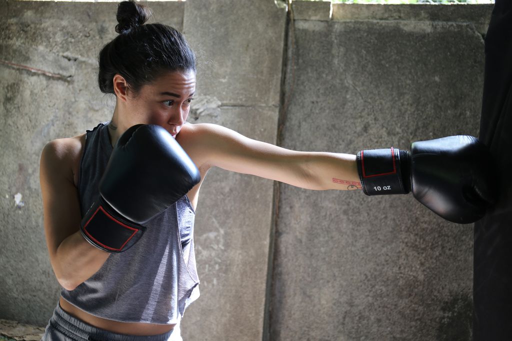 Young Filipino woman boxing in her garage outside.