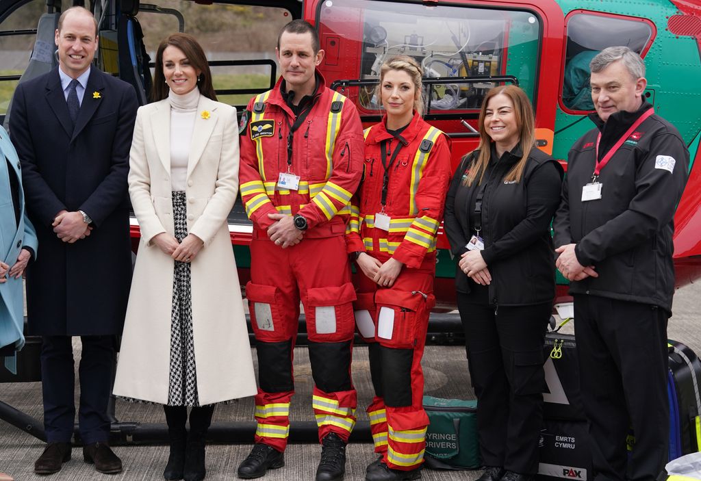 Prince William and Kate Middleton standing with people in red uniform