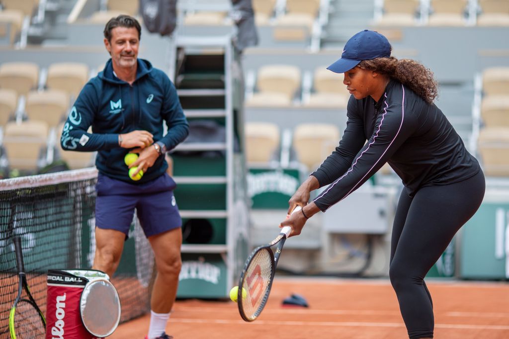 Serena Williams in black leggings and blue cap practicing tennis with coach Patrick Mouratoglou while training on Court Philippe-Chatrie