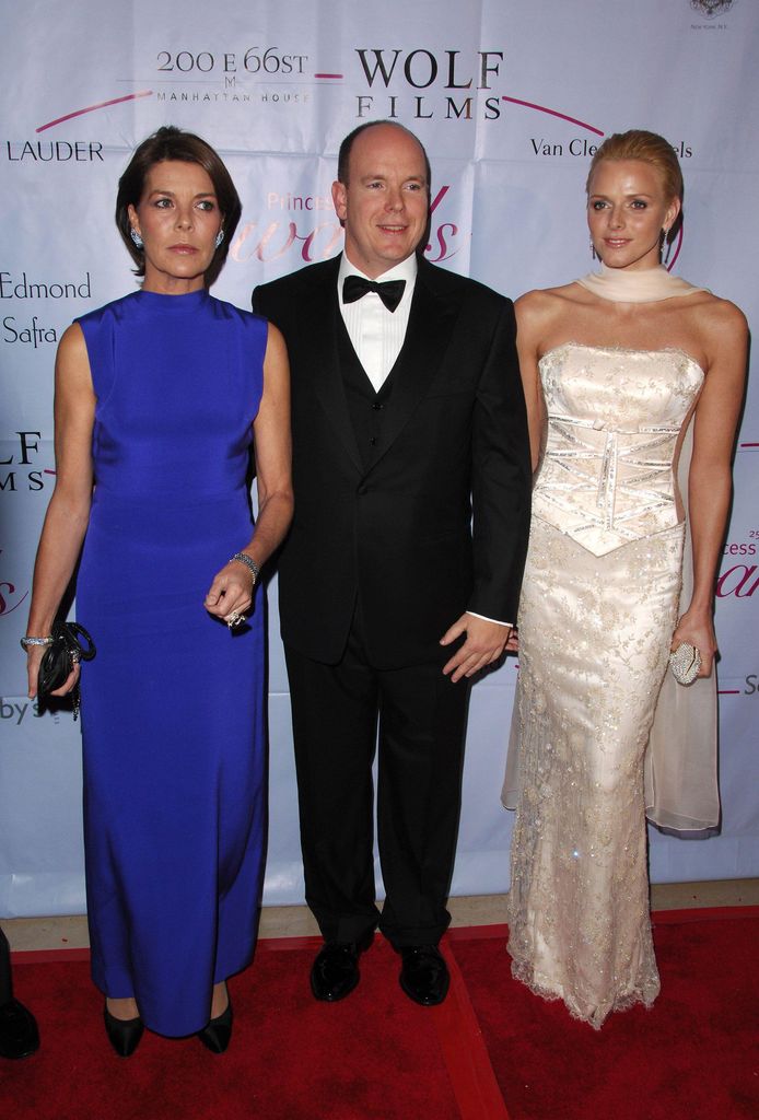 three people posing on red carpet at gala 