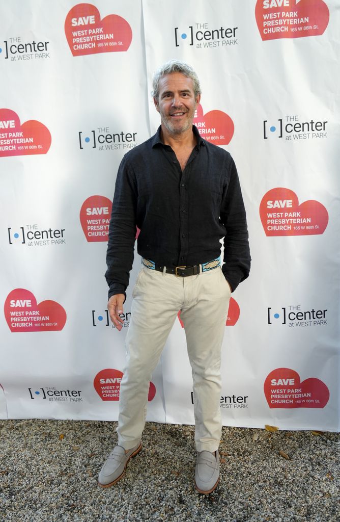 Andy Cohen in black shirt and white pants