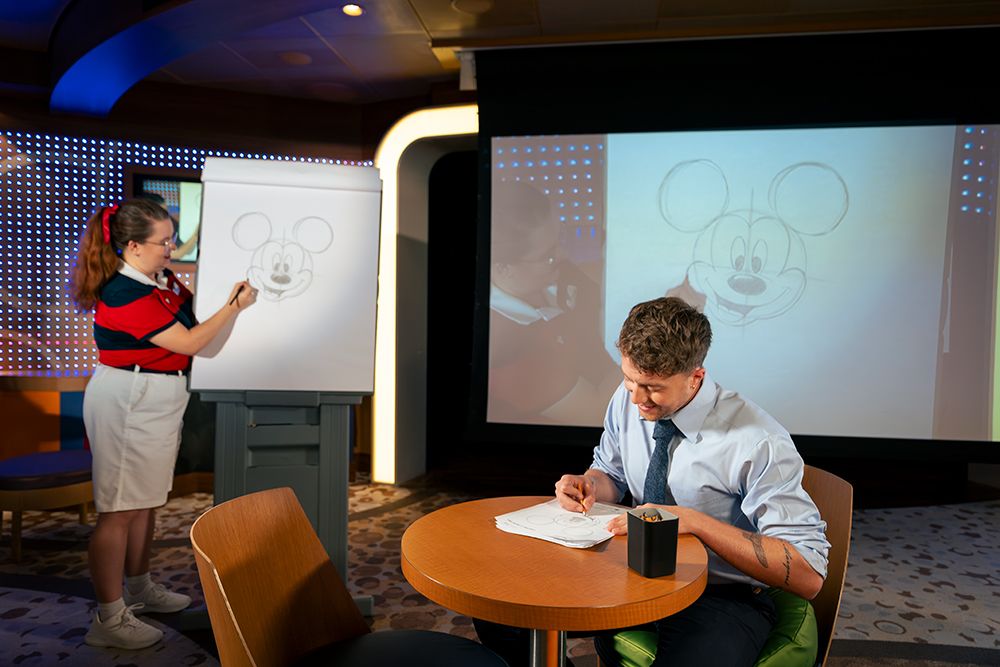 Roman Kemp taking a drawing lesson on the Disney Dream