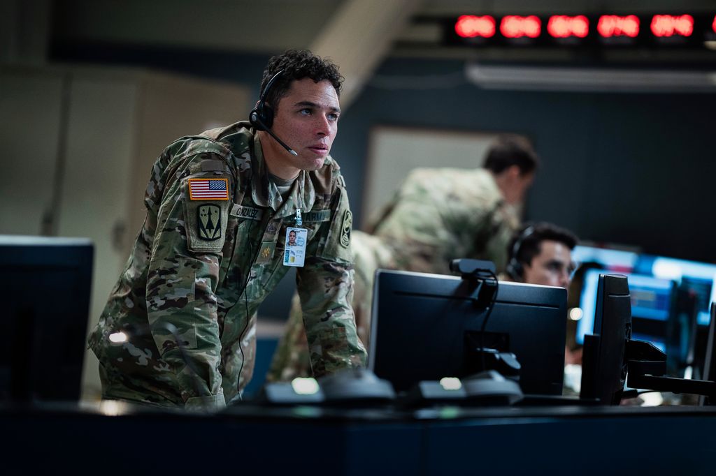 man in military uniform standing over computer