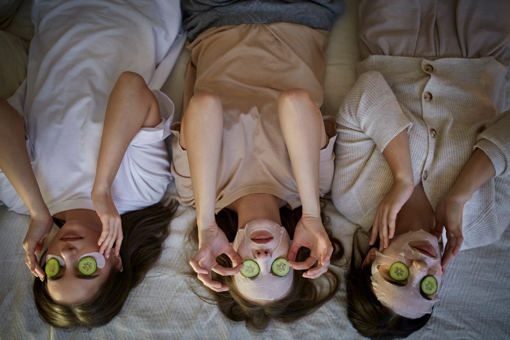 Three female friends lying down with beauty masks