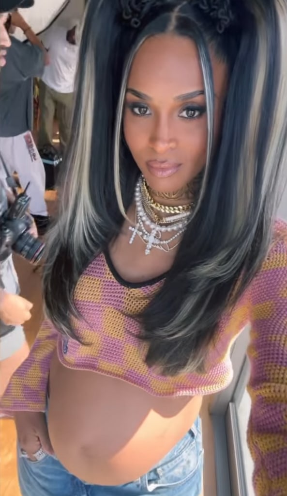 Still from a video shared by Ciara behind the scenes on a photoshoot, where she is showing off her growing baby bump in a pink and orange checkered crop top