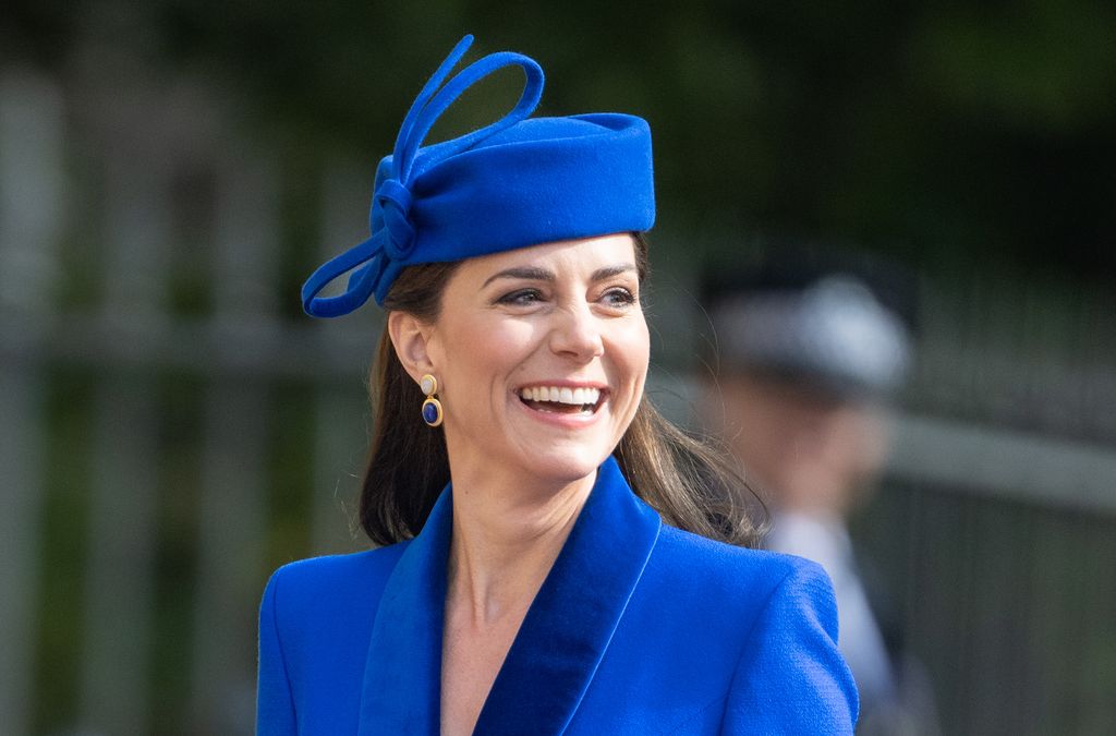 Kate Middleton sorrindo usando chapéu e casaco azuis