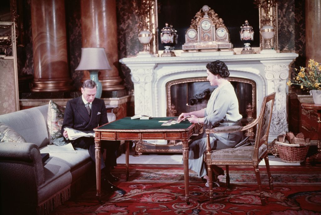 woman playing cards at table and man sat on sofa