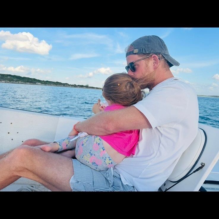 A photo of Prince Harry kissing Lilibet on the head on a boat