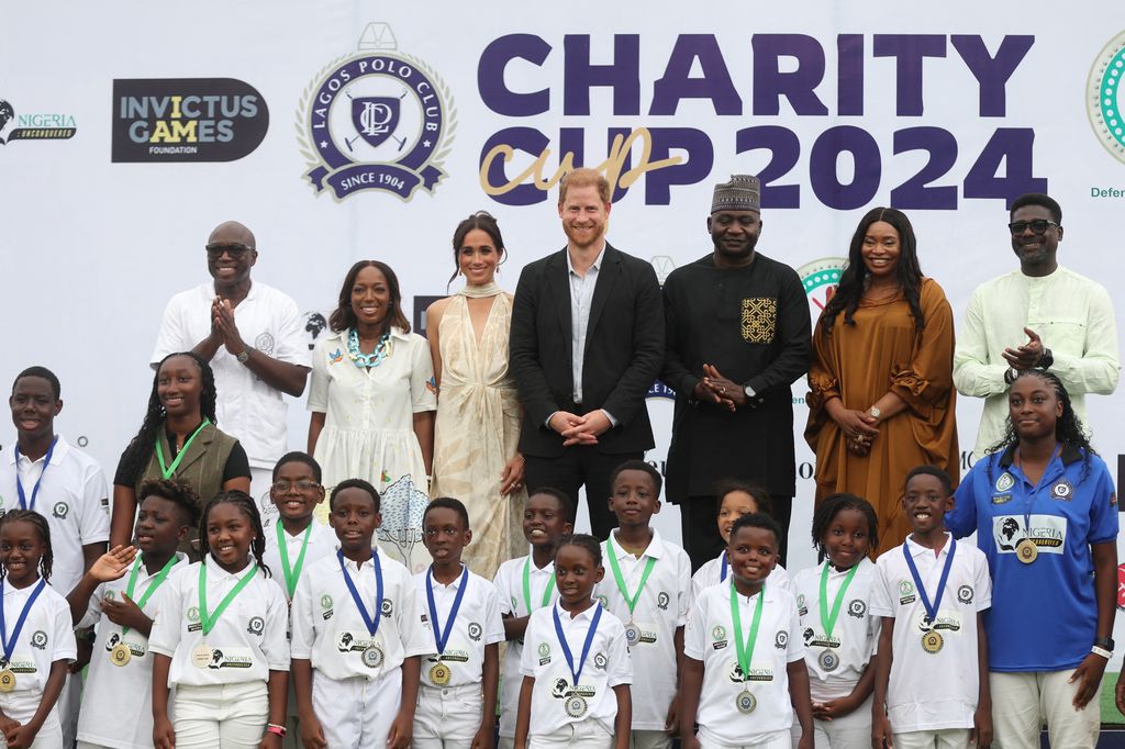 agos Polo Club President Bode Makanjuola (L), his wife Moyo Makanjuola (2ndL), Britain's Meghan (3rdL), Duchess of Sussex, Britain's Prince Harry (4thL)), Duke of Sussex, Nigeria Chief of Defense Staff Christopher Musa (3ndR), his wife Lilian Musa (2ndR) and Regional head of Equity Research for West Africa at Standard Bank group, Muyiwa Oni (R) pose for a photo with children after a charity polo game at the Ikoyi Polo Club in Lagos on May 12, 2024 as they visit Nigeria as part of celebrations of Invictus Games anniversary. (Photo by Kola Sulaimon / AFP) (Photo by KOLA SULAIMON/AFP via Getty Images)