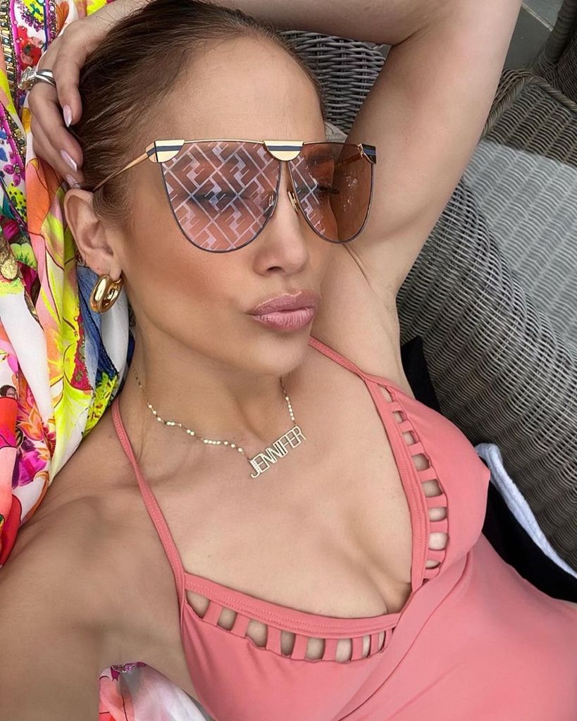 Jennifer Lopez in pink swimsuit and oversized sunglasses sunbathing