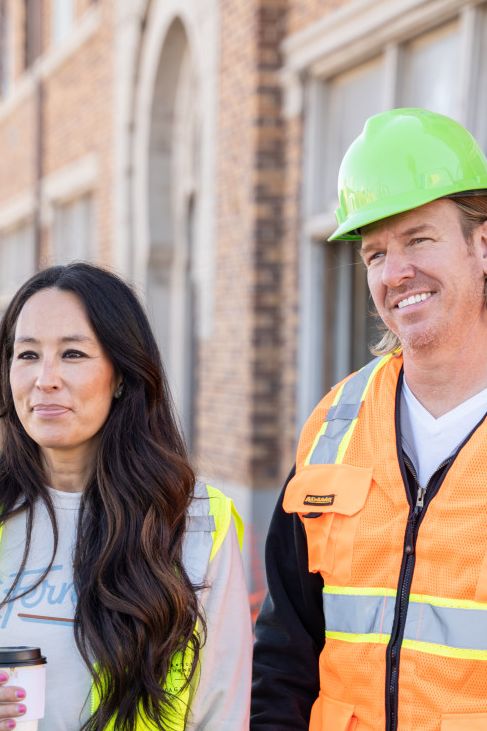  Joanna Gaines and Chip Gaines wear hard hats and high vis vests outside a property
