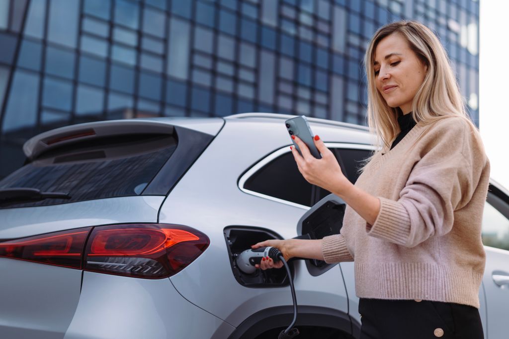  Young woman with smartphone waiting for car charging