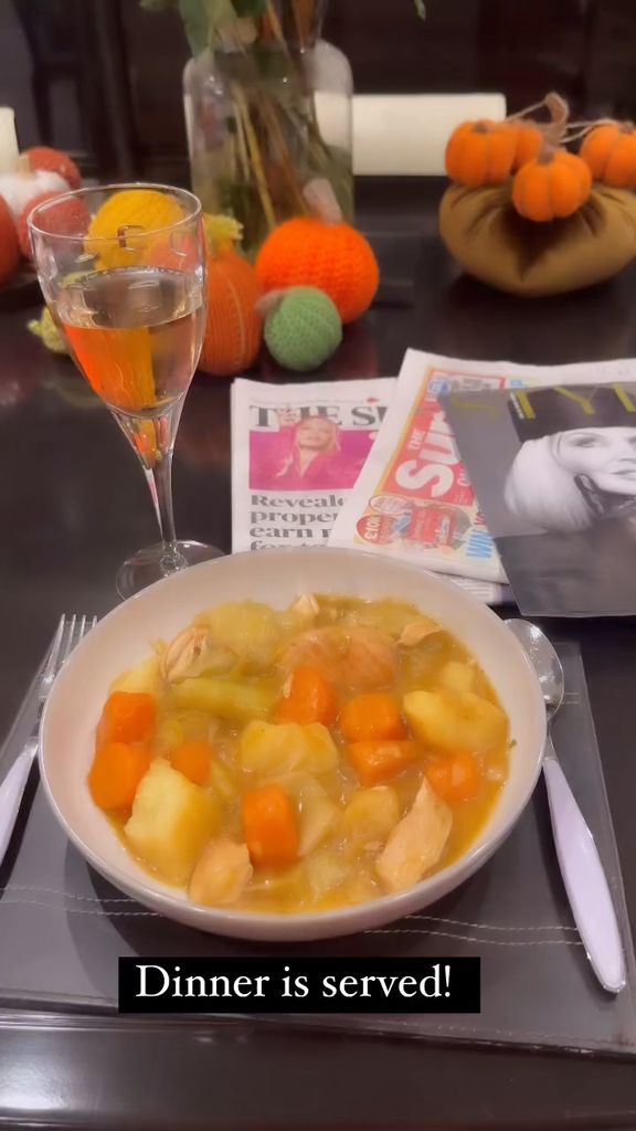 A photo of a casserole along with a glass of white wine and three sunday papers