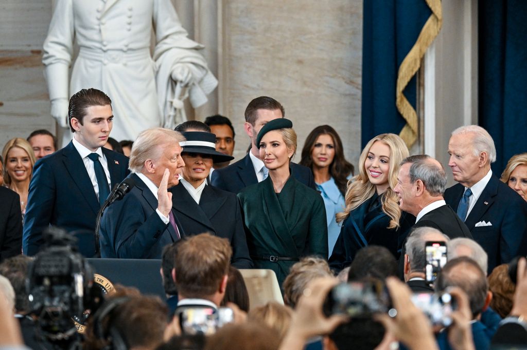 U.S. President-elect Donald Trump is sworn in by Supreme Court Chief Justice John Roberts at his inauguration while Ivanka Trump dressed in green looks on