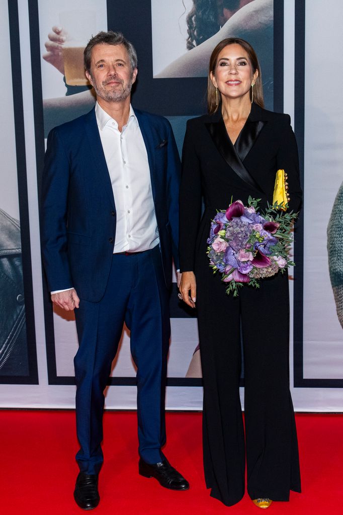 King Frederik and Queen Mary on red carpet in smart dress