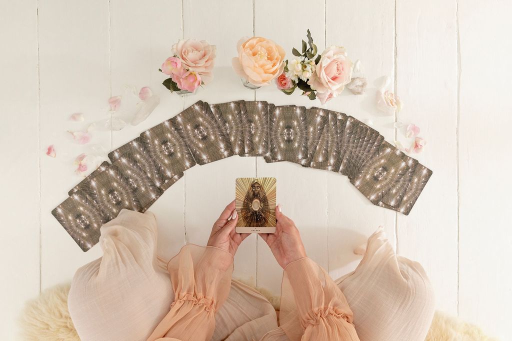 Rebecca holding an oracle card she's just pulled from the pile in front of her