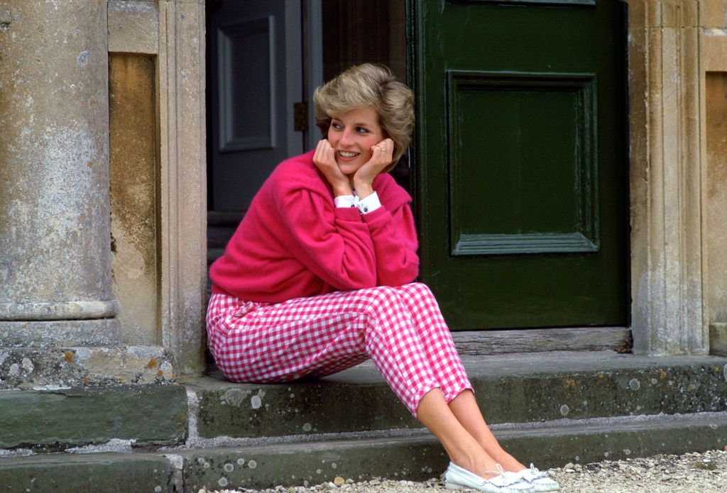 Princess Diana sitting on a set of stairs in a pink outfit