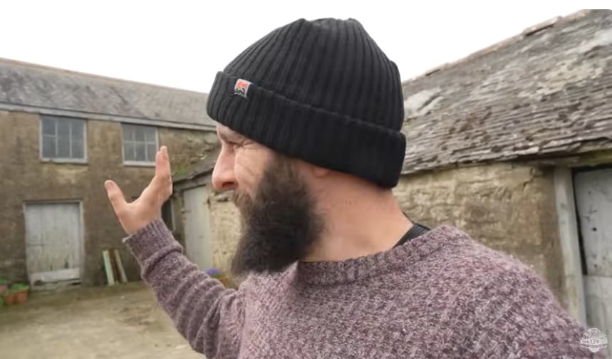 man with black hat on outside of barn 