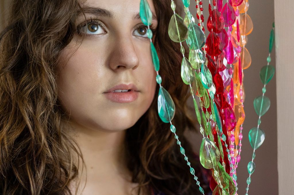 Portrait de la belle jeune femme debout à côté du rideau de perles