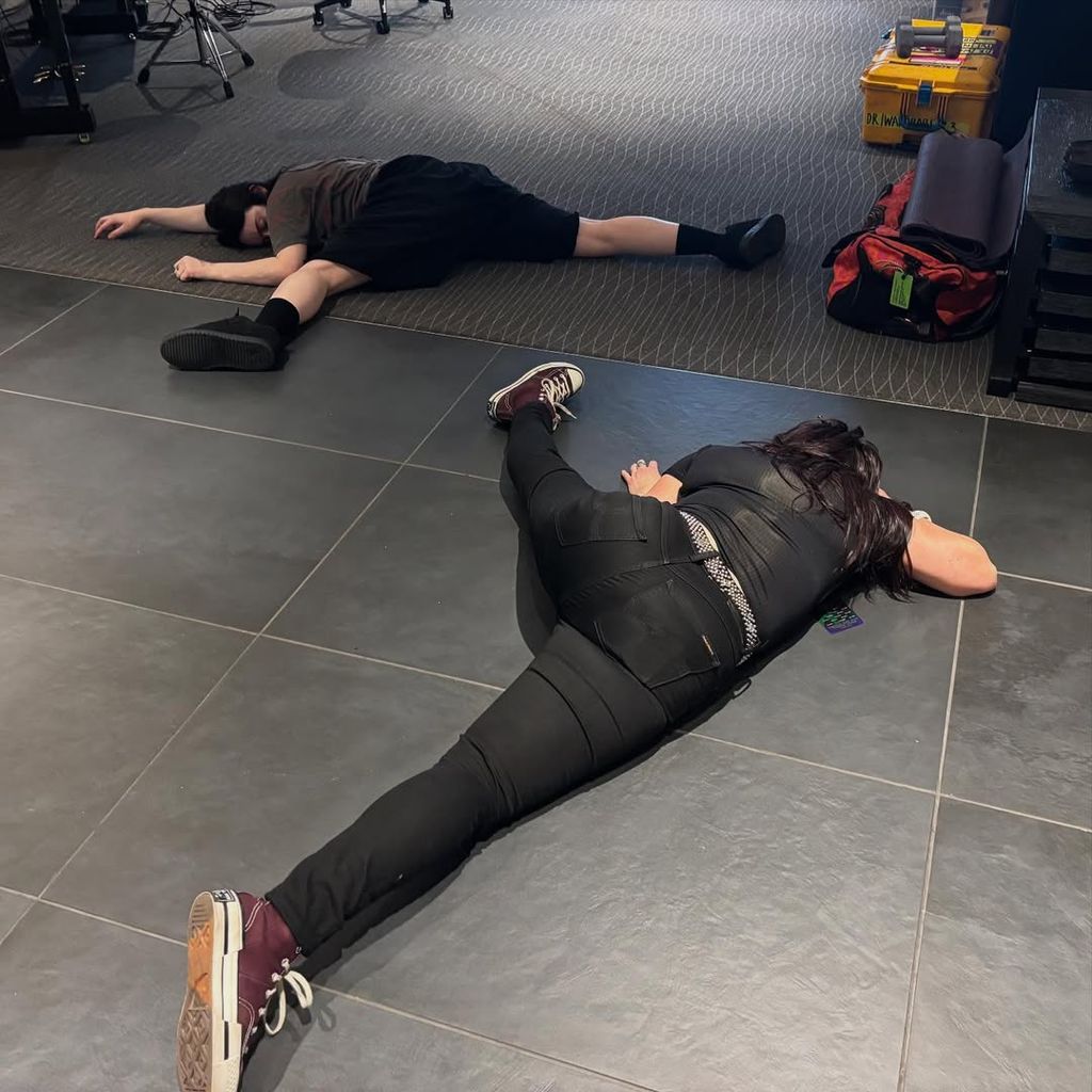 Billie Eilish and one of her tour's performers lie on the floor tired backstage in a photo shared on Instagram