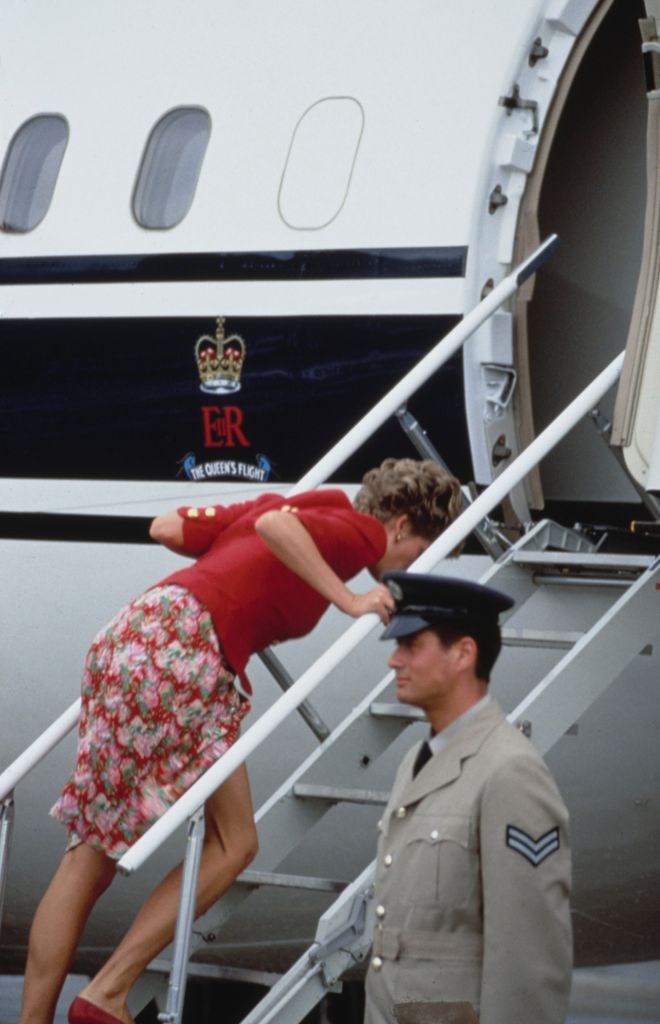 Diana, Princess of Wales (1961-1997), wearing a red top with gold buttons and a floral pattern skirt, struggles to climb the boarding steps as she visits Minchi Point on the Khyber Pass in Pakistan, 26th September 1991.