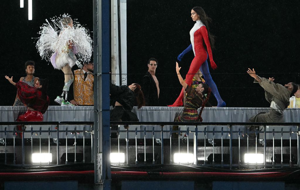 TOPSHOT - A model presents creations while walking a catwalk erected along the Passerelle Debilly bridge on the Seine river during the opening ceremony of the Paris 2024 Olympic Games in Paris on July 26, 2024.