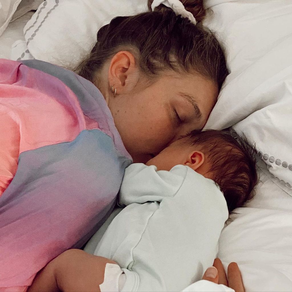 Gigi Hadid in a pink top napping in bed with baby Khai