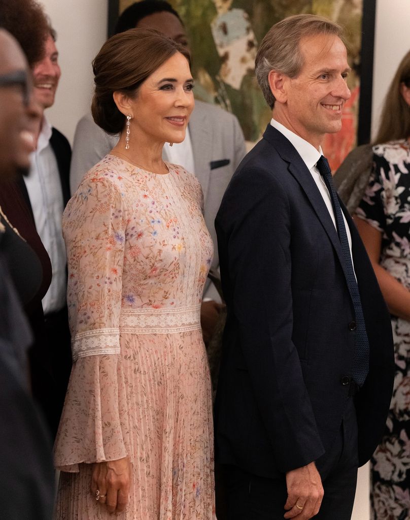 queen mary in pink dress posed smiling beside man