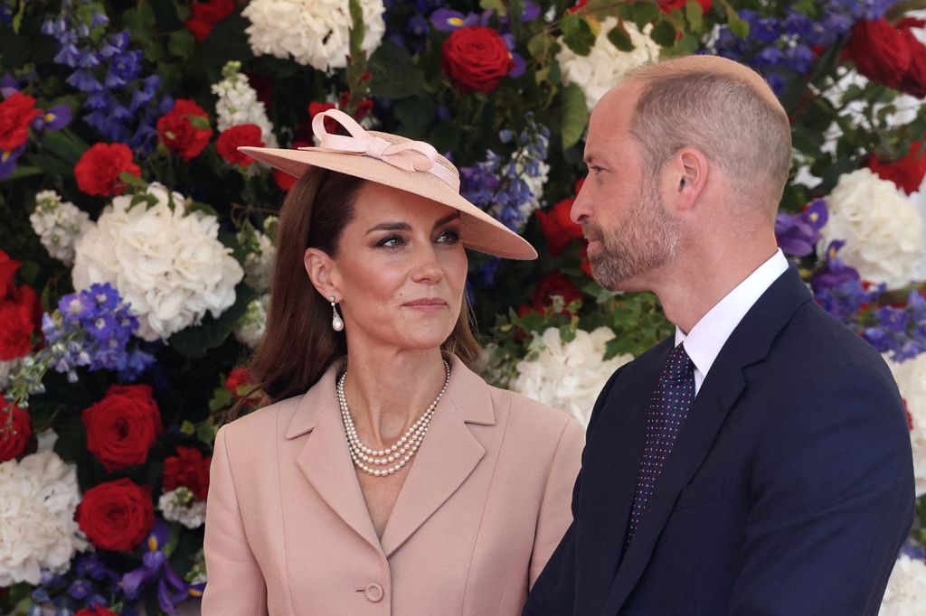 Kate smiling at William in front of floral wall