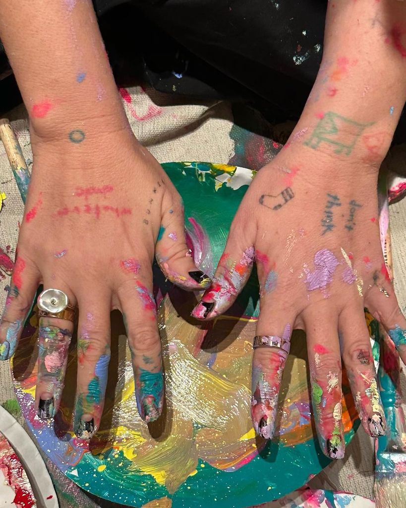 Sia's hands covered in paint without an engagement ring