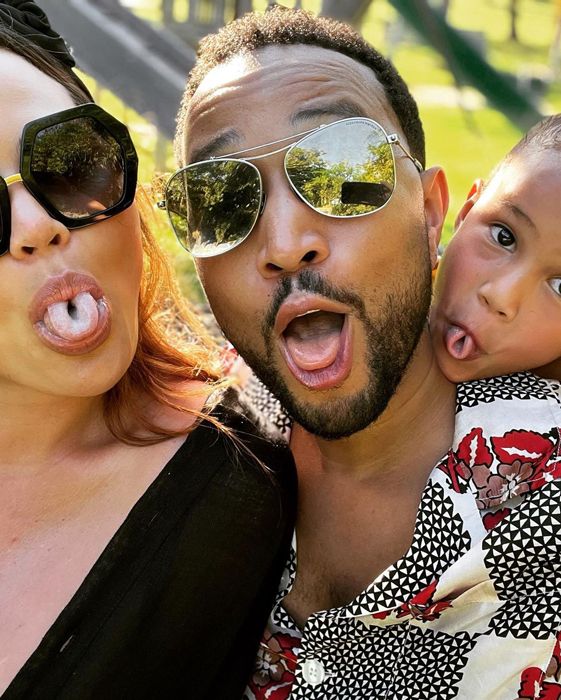 Chrissy Teigen, John Legend and their child poking their tongues out