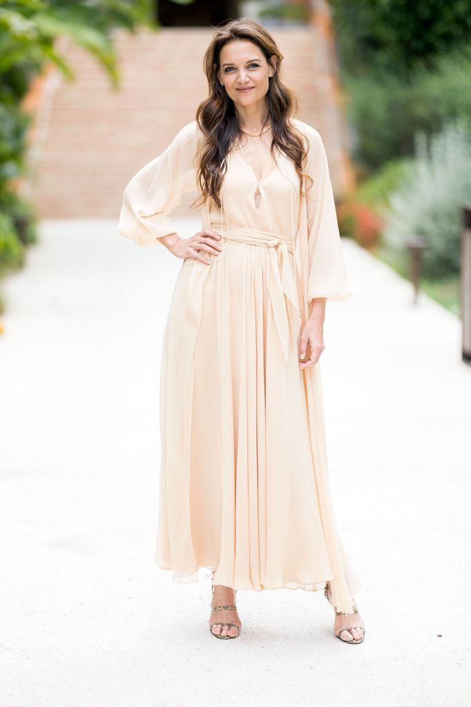 Katie Holmes wears a cream silky maxi dress with belted detail, teamed with snakeskin heels