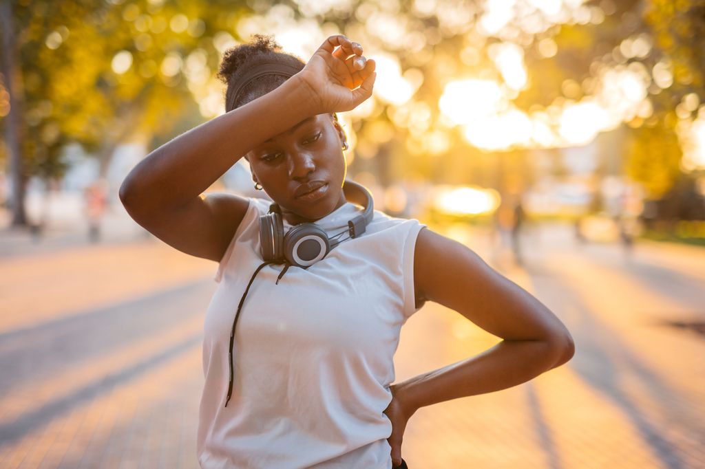 Beautiful young black woman exhausted after jogging in the park.